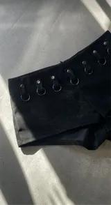 Short negro con cintura alta y detalle de argollas metálicas en la parte superior.