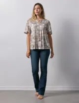 Blusa de tejido elastizado con estampado geométrico en tonos beige y blanco. Tiene cuello redondo con escote en V y lazo de ajuste, y mangas cortas amplias. Marca Cupio.