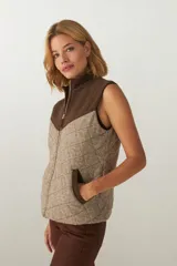 Chaleco corto de lana color marrón con diseño acolchado en forma de rombos. Presenta cuello alto, cierre frontal con cremallera dorada, dos bolsillos laterales y canesú en color marrón oscuro. Hecho en Uruguay.