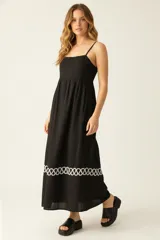 Vestido largo negro de viscosa con breteles finos, corte evasé, frunces en el busto y detalle de bordado blanco en el ruedo.