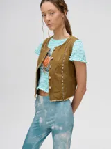 Chaleco marrón de denim con apliques metálicos y flecos en el ruedo.