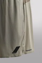 Shorts de entrenamiento color verde oliva, confeccionado en tejido técnico ligero y elástico con perforaciones. Tiene forro interior, cintura elástica ajustable con cordón, bolsillos laterales, bolsillo trasero con cierre de cremallera, bajo con aberturas laterales y logo estampado en la pierna.