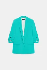 Blazer marrón con cuello solapa y hombreras. Manga tres cuartos con trabilla y botón dorado. Bolsillos delanteros con solapa.