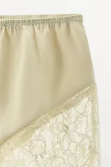 Shorts color beige de tiro alto confeccionado en tejido satinado con cintura elástica y detalle de encaje en el ruedo.