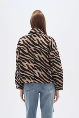 Campera estilo camisa (shacket) cropped, con cuello, cierre frontal y dos bolsillos con tapa en el pecho. Presenta un estampado de cebra en tonos beige y negro.
