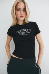 Remera negra entallada corta en punto acanalado de algodón con estampa frontal de pastelería francesa. Costuras planas para una comodidad óptima.