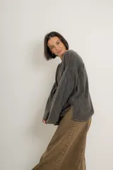 Buzo verde militar de tejido liviano con acabado gastado, corte oversize, cuello bote y mangas largas con hombro caído.