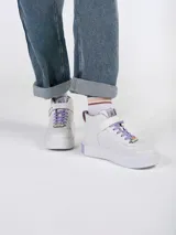 Zapatillas blancas de caña alta con detalles de la serie Friends, cordones lilas y cierre de velcro con el nombre de la serie.