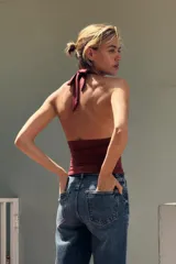 Top negro de cuello halter ajustable con lazadas, espalda descubierta, detalle de aplicación metálica en el delantero y drapeado lateral.