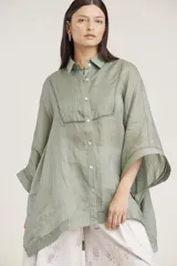 Camisa verde claro de lino con corte oversize, cuello camisero, cierre frontal con botones y mangas anchas con puños.