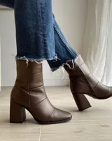 Botín de cuero color marrón con caña media, punta fina y taco geométrico de 10 cm.