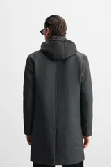 Abrigo gris oscuro de corte recto, con cuello doble y capucha desmontable con cremallera. Tiene manga larga, bolsillos laterales y abertura central en la espalda. El cierre frontal es con cremallera oculta por solapa con botones a presión.