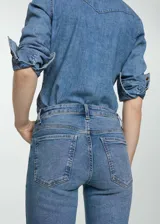 Pantalón de jean azul de corte cropped y acampanado, tiro alto, con cinco bolsillos y cierre de cremallera y botón.