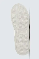 Zapatillas deportivas de estilo retro, color beige y marrón, con cordones y suela gruesa.