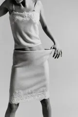 Top de punto color crema claro, corte recto y ajustado, con detalle de encaje floral bordado en el escote. Posee tirantes ajustables de color beige claro.