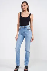 Pantalón de jean celeste con corte recto, tiro alto, detalles de roturas en las rodillas y cadena dorada decorativa en la cintura.