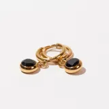 Aros dorados tipo argolla con dije circular colgante de piedra negra.