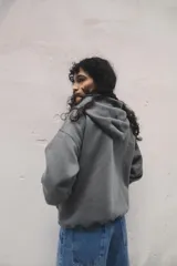Campera gris con cierre frontal, capucha con cordones ajustables, bolsillos tipo canguro y puños y cintura acanalados.
