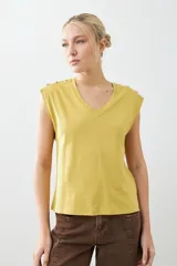 Remera verde pistacho de corte recto, con cuello en V y botones decorativos en los hombros.