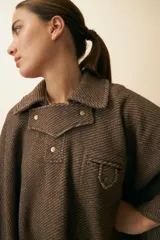 Poncho unisex de lana fina color marrón claro, con cuello polo, cartera con broches a presión y bolsillo ojal.