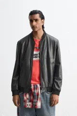 Cazadora bomber negra de efecto piel, corte relaxed fit, con cuello y puños de rib elástico, cierre frontal con cremallera, bolsillos laterales de doble vivo y bolsillo interior.