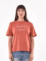 Remera color ladrillo con estampado de olas y texto "Waves of Life" en blanco.
