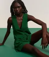 Chaleco corto color marrón, de corte sastre, con escote en V, doble botonadura y lazo en la espalda.