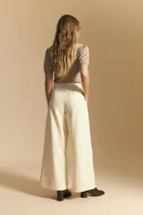 Pantalón ancho de tiro alto, color negro, con costuras contrastantes en blanco que definen los bolsillos y los bordes.