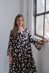Vestido largo de corte amplio con estampado animal print en tonos negro y beige, cuello camisero y mangas largas.