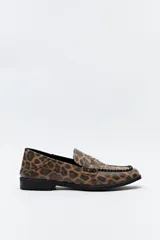 Mocasines negros de símil cuero texturizado, con punta cuadrada, detalle de bordado a tono en la capellada y taco de 2,5cm.