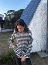 Blusa de manga larga con estampado de cuadros vichy en blanco y negro. Presenta un cuerpo fruncido con smock elástico y volantes en los puños.