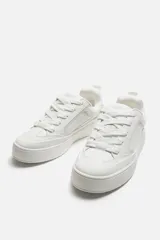 Zapatillas deportivas blancas de estilo skate con cordones gruesos y suela con plataforma.