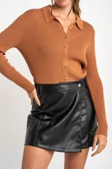 Cardigan negro de tejido de punto acanalado, con cuello polo, corte al cuerpo y cierre frontal con botones.