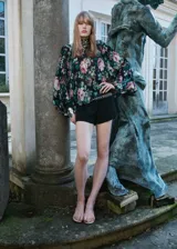 Blusa de gasa con estampado floral, cuello alto, manga larga con volantes y cierre de lazo en la parte posterior.