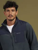 Campera de micropolar gris con detalles en negro en la parte superior y cuello. Tiene cierre frontal, bolsillos laterales con cierre y un bolsillo en el pecho con cierre.