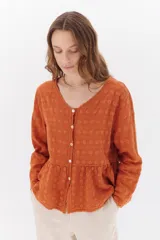 Camisa color ladrillo con textura arrugada y bordados a tono, escote en V, mangas largas y cierre frontal con botones.