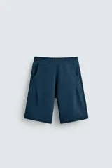 Bermuda azul petróleo de corte relaxed fit, confeccionada en algodón. Tiene cintura elástica ajustable con cordón, bolsillos laterales y un bolsillo trasero.