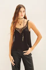 Top tipo musculosa confeccionado en modal satén, color negro, con terminación de calado en el escote delantero y en la espalda, acompañado de bordados a tono.