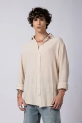 Camisa blanca de lino con cuello clásico, manga larga con puños abotonados y corte holgado. 