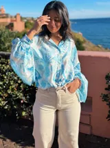 Camisa celeste con estampado abstracto, de corte amplio, cuello camisero y mangas largas abullonadas con puños elásticos.