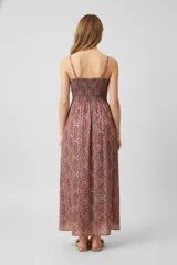 Vestido largo con estampado paisley en tonos verdes, marrones y rojizos. Tiene breteles finos, escote en V y corte recto con punto smock en la cintura.