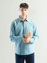 Camisa de manga larga color verde oliva, confeccionada en algodón. Tiene corte clásico, bolsillo en el lado izquierdo del pecho y cierre con botones.