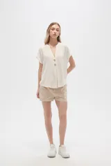 Blusa color crudo de viscosa, corte holgado, con cuello en v y cierre frontal con dos botones de madera.