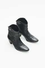 Bota corta de cuero negro con taco medio y punta fina. Presenta recortes grabados en el mismo material en el cuerpo de la bota.