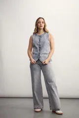 Chaleco de jean celeste con efecto lavado, sin mangas, con cuello redondo y cierre frontal con botones.