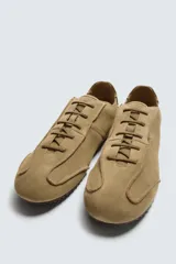Zapatilla de cordones color negro, con capellada de cuero serraje, horma redonda y suela ultrafina.