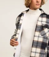 Campera trucker masculina de franela a cuadros en tonos blanco, negro y gris, con cuello inglés, abotonado delantero, bolsillos con solapa en el pecho y bolsillos laterales. Interior forrado en sherpa.