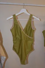 Traje de baño entero verde pistacho con escote cruzado y ribete color beige.