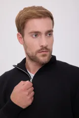 Sweater negro de punto con cuello alto y cierre de cremallera parcial.