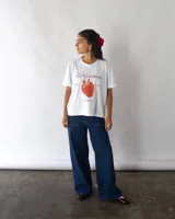 Remera blanca de manga corta con estampado de frutilla y texto en color rojo.